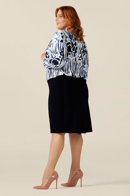 A size 18, plus size woman wears a collarless open front jacket with long sleeves. In navy and white jersey, this corporate jacket is comfortable office wear. Made in Australia to a high quality standard, the Yuri work wear jacket is women's corporate wear at it's best!